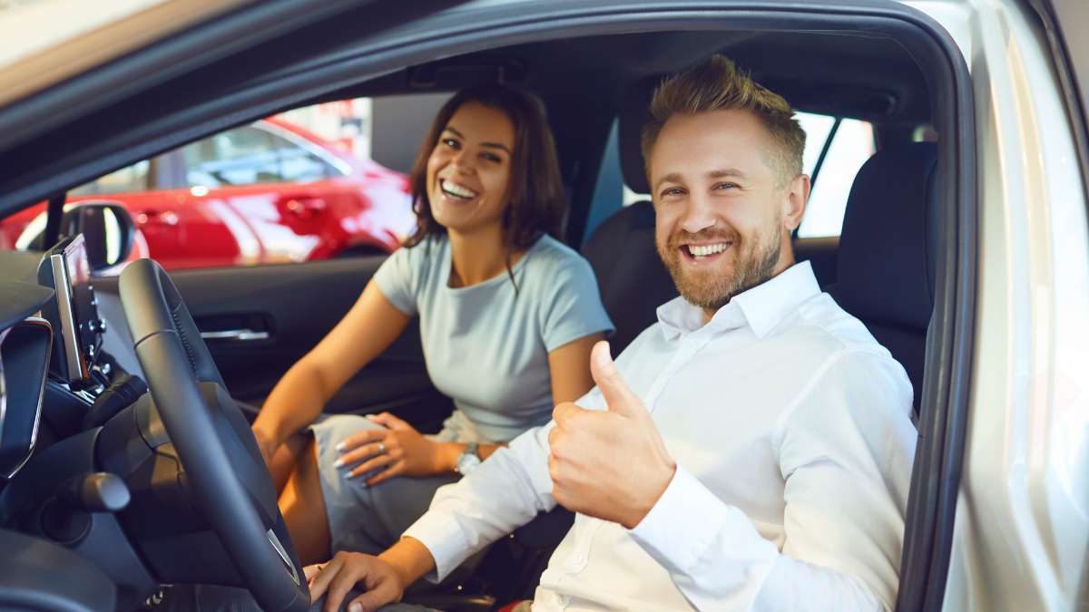 Happy couple driving car saving money on auto insurance 2026